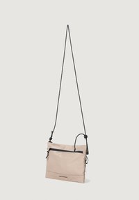 Bolso cruzado de un beige claro, hecho de material de nailon, con un bolsillo con cremallera, correa ajustable negra y un diseño minimalista.