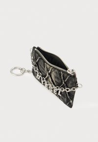 Μαύρο υφασμάτινο θήκη με καπιτονέ σχέδιο, ασημένιο εξάρτημα, κλείσιμο με φερμουάρ και διακοσμητική αλυσίδα. Διαθέτει την επιγραφή "DIESEL" με ασημένια γράμματα μπροστά.