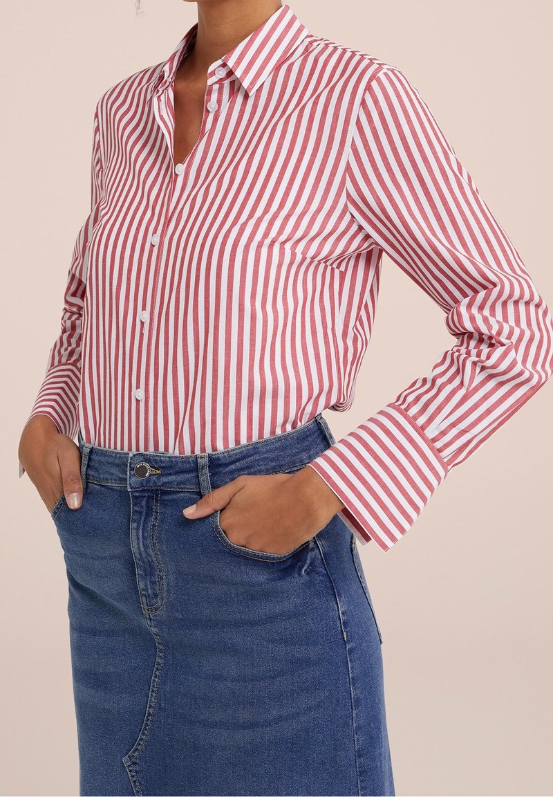 Red and white striped button-up shirt with a collar and long sleeves, paired with a blue denim skirt, front pocket visible.