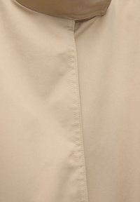 Pannello in tessuto beige con texture liscia, che mostra un dettaglio di cuciture verticali. Design minimalista senza ulteriori motivi o accessori.