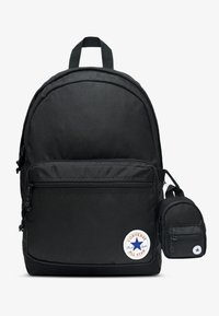 Černý batoh z odolné tkaniny s kulatým tvarem, přední kapsou na zip a malým odnímatelným pouzdrem s logovou nášivkou.