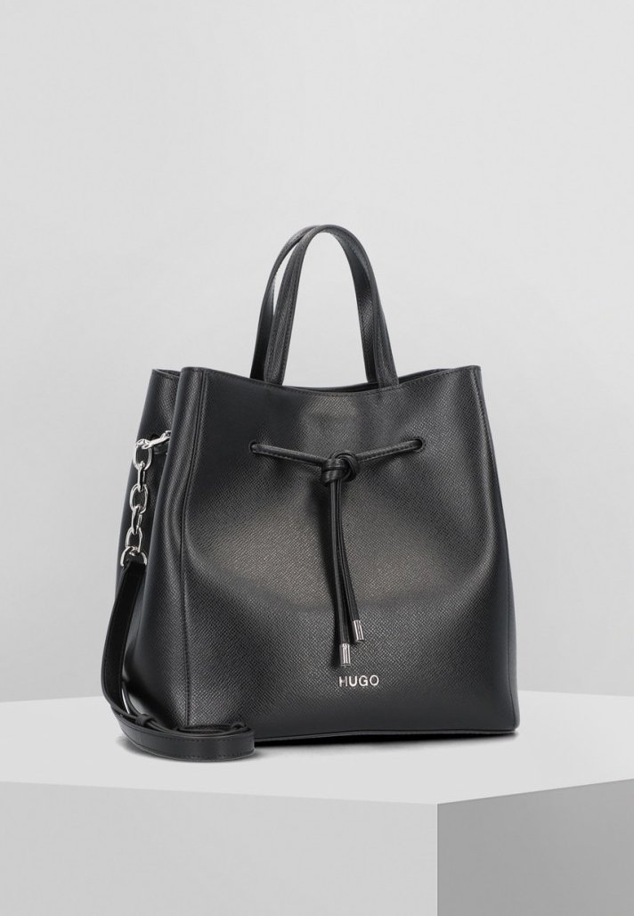 Sac fourre-tout en cuir texturé noir avec fermeture à cordon, double poignée, bandoulière avec détail chaîne et logo "HUGO" sur le devant.