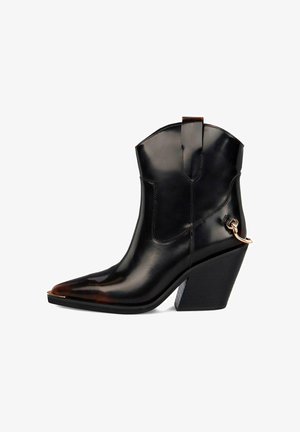 Bota de cuero negra hasta el tobillo con punta afilada, tacón alto y cuadrado, y acento decorativo de cadena de metal. Textura suave con acabado brillante.