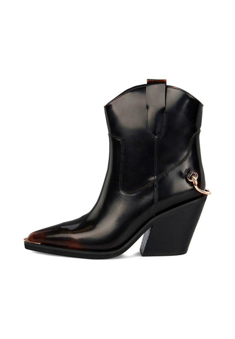 Bota de cuero negra hasta el tobillo con punta afilada, tacón alto y cuadrado, y acento decorativo de cadena de metal. Textura suave con acabado brillante.