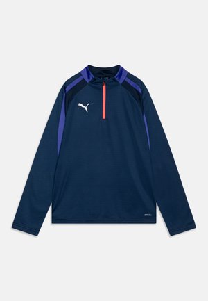 Marineblauw sporttop met lange mouwen, kwart-rits kraag, paarse accenten en een wit logo op de borst. Gemaakt van vochtregulerende stof.