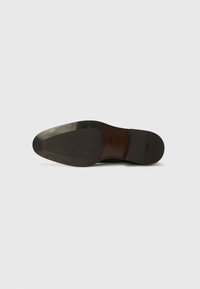 Suela de zapato de cuero negro brillante, con un acabado suave, forma de punta afilada y detalle de logo en relieve. Tacón texturizado para un mejor agarre.
