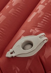 Cuscino gonfiabile rosso con una texture liscia. Presenta un sistema valvolare grigio chiaro con un'apertura circolare per il gonfiaggio e lo sgonfiaggio.