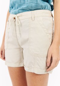 Lichtbeige shorts van een zachte stof, met een trekkoord in de taille, opgerolde zomen en zijzakken met zichtbare stiksels.