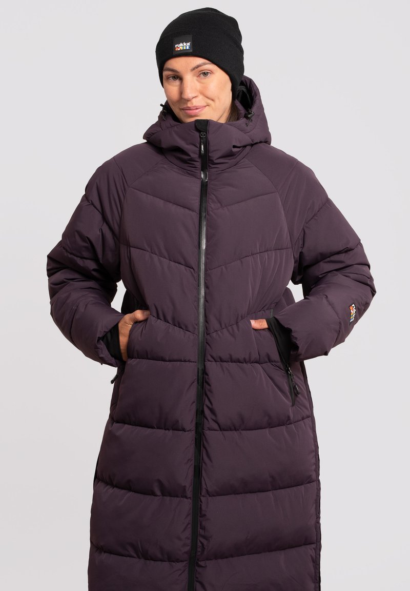 Lang, polstret lilla vinterl coats med høj krave, frontlynlås og sidelommer. Tekstureret quiltedesign med et logoaccent på ærmet.