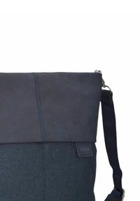 Borsa blu scuro con patta superiore liscia in pelle e corpo in tessuto texturizzato. Dotata di tracolla regolabile e una piccola etichetta con il logo.