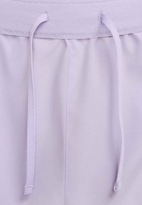 Pantalones cortos deportivos de color lila claro con cintura ajustable, textura suave y detalles cosidos en la cintura y las costuras laterales.