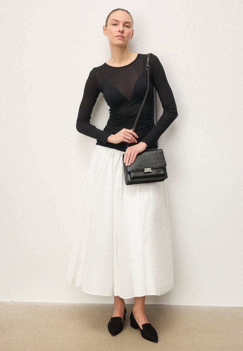 Must pika varrukaga pluus läbipaistva paneeliga, valge midi seelik ja must krokodillinaha musteriga käekott. Komplekti kuuluvad ka mustad teravate ninadega kingad.