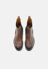 Brune skinn Chelsea-støvler med glatt finish, elastiske sidedetaljer og brogue-detaljer langs tåhetten og sidene.
