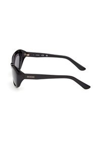 Lunettes de soleil noires Guess avec des montures rectangulaires épaisses et des verres foncés, affichant le logo de la marque sur la branche, sur fond blanc.