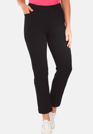 Pantaloni neri con elastico in vita, dal taglio dritto, dotati di tasche frontali e una texture liscia e morbida. Abbinati a sneakers bianche.