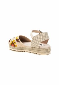 Sandale espadrille beige avec broderie florale en jaune et marron. Équipée d'une sangle arrière tissée et d'une semelle enveloppée de jute.