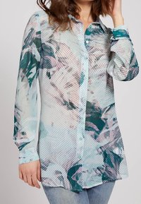 Blusa a maniche lunghe in un tessuto leggero e trasparente, caratterizzata da una stampa astratta multicolore con pois e un’apertura con bottoni davanti.
