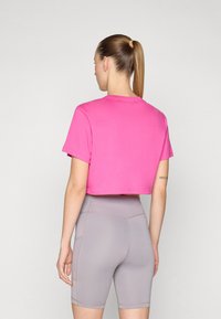 Vaaleanpunainen lyhythihainen cropped t-paita pehmeästä kankaasta, yhdistettynä vaaleanharmaisiin korkeavyötäröisiinshortseihin, joissa on ompeluyksityiskohtia.