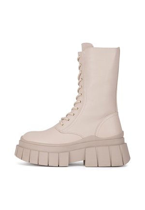 Beżowe, wiązane botki za kostkę na masywnej platformie, z gładką fakturą i okrągłym noskiem. Z boku suwak ułatwiający zakładanie.