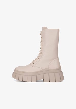 Beżowe, wiązane botki za kostkę na masywnej platformie, z gładką fakturą i okrągłym noskiem. Z boku suwak ułatwiający zakładanie.