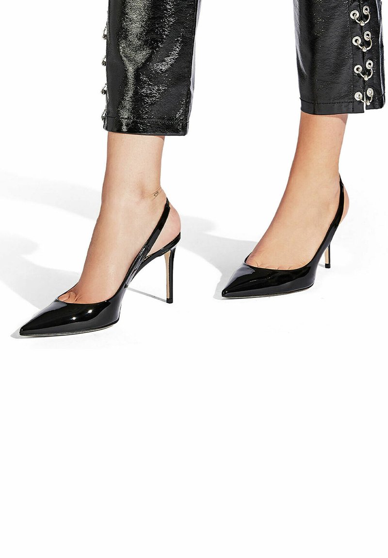 Zapatos de tacón de charol negro con tiras traseras y puntera afilada, y un delgado tacón de aguja. Diseño elegante con un acabado suave y brillante.