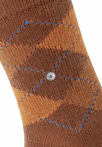 Calzino lavorato a maglia marrone con un motivo a diamante in marrone chiaro e accenti blu, impreziosito da un piccolo badge metallico con logo sul lato.