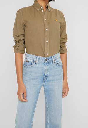 Olive green button-up shirt with a collared neck, paired with light blue straight-leg jeans. Features an embroidered logo, fitted cuffs, and light denim texture.