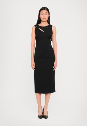 Black midi dress with a sleeveless design, featuring a side cutout and decorative hardware accents. Fitted silhouette, smooth fabric texture.