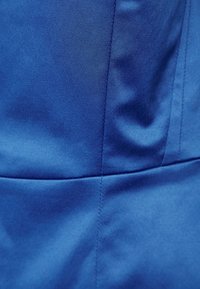 Modrá látka s hladkým povrchem, s jemnými záhyby, horizontálními a vertikálními švy a strukturovaným designem.