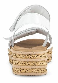 Sandales blanches avec une large sangle, fermetures velcro réglables et une semelle en liège stratifiée avec des détails texturés. Bout arrondi avec une finition lisse.
