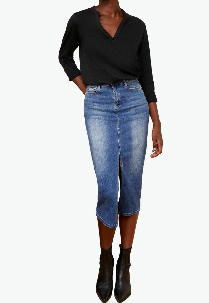 Denimlifeiden polvipitkä kynähame, jossa on edessä halkio, vaalealla pesulla ja sinisellä sävyllä. Yhdistetty mustaan pitkähihaiseen paitaan ja nilkkureihin.