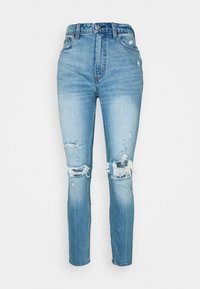 Jeans de mezclilla azul claro con cintura alta, corte ajustado y varias áreas desgastadas, con dobladillos deshilachados y un leve desvanecimiento.