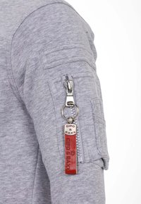 Grijze fleece sweatshirt met een ritszak op de mouw, voorzien van een metalen trekker, leren sleutelhangeraccent met reliëftekst en gestructureerde stof.