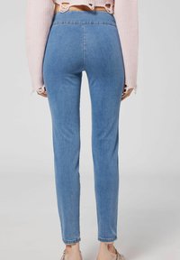 Ljust blå högmidjade jeans i denim, med en smal passform och sömlös design. Hemsömmarna är lätt uppvikta.