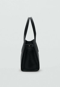 Black leather tote bag with double handles and side strap detail, shown from the side against a plain light background.