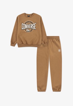 Completo di felpa e pantaloni della tuta marrone. La felpa presenta un grande logo "Converse" e polsini a coste. I pantaloni hanno una vita elastica e il logo.