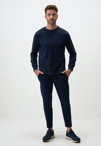 Felpa blu navy e pantaloni affusolati abbinati, realizzati in un tessuto leggero e morbido. Presenta maniche lunghe e scollatura rotonda, con tasche.