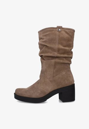 Stivali alti in suede color cammello con un design svasato, tacco a blocco e cuciture visibili. Presentano un bottone decorativo sul gambale.