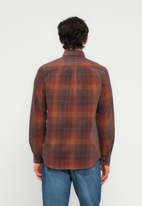 Πουκάμισο με μακριά μανί κια και καρό μοτίβα σε καφέ και πορτοκαλί αποχρώσεις, με γιακά που κουμπώνει, πιέτα στην πλάτη και στρογγυλεμένη ραφή. Κατασκευασμένο από ελαφρύ ύφασμα.