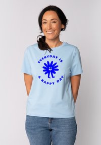 Himmelblaues Baumwoll-T-Shirt mit kurzen Ärmeln, das ein blaues Grafikdesign und den Text "JEDER TAG IST EIN GLÜCKLICHER TAG" in fetter Schrift zeigt.