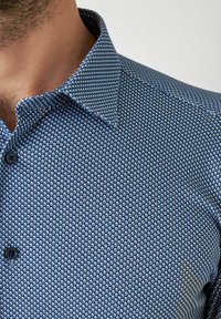 Blauw shirt met patroon, voorzien van een getextureerd ontwerp, knoopsluiting en een klassieke kraag. De stof heeft een subtiele glans.