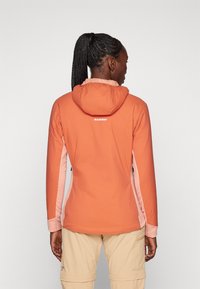 Hooded, orange outdoor jacket with pink side accents. Made of stretchy material, featuring a fitted design and branding at the back.