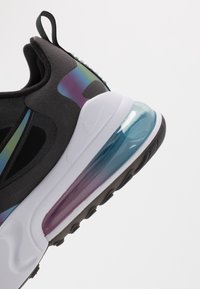 Černý Nike sneaker s prodyšnou a hladkou texturou; obsahuje čirou vzduchovou odpružovací jednotku s modrými a purpurovými akcenty; zaoblený tvar.