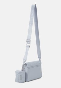 Jasnoniebieska torebka na ramię o pikowanej fakturze, z odpinaną mini saszetką i regulowanym paskiem z logo marki. Z elementami w kolorze srebrnym.