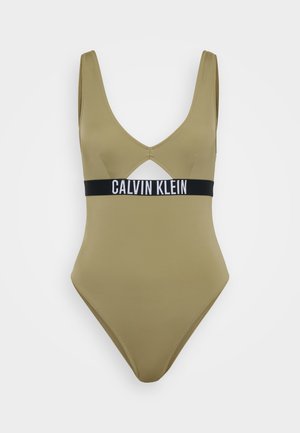 Olijf groene badpak met een diepe V-hals en uitsparingen. Bevat een zwarte band met het logo "CALVIN KLEIN". Soepele stof textuur.