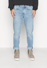 Lichtblauwe jeans met een slim fit en opgerolde pijpen, gemaakt van denim. De tailleband heeft een knoop en een ritssluiting met vijf zakken.