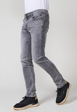 Šedé džíny z denimu slim fit, s jemným vyblednutím, pěti kapsami a klasickým zapínáním na knoflík. Kompletované s černými atletickými teniskami.