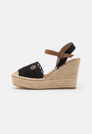 Sandalia cuña esparto negra trenzada con puntera beige y correa marrón en el tobillo, con plataforma envuelta en yute texturizado.