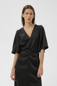 Melna kleita ar V veida izgriezumu, īsām zvana formas piedurknēm un krokojumu priekšpusē. Izgatavota no gludas, strukturētas auduma.