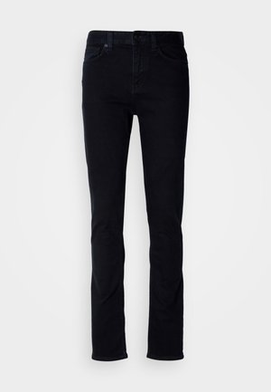 Mustad teksased, mis on slim fit lõikega, viie taskuga disainiga, nähtava õmblusega ja nööbiga sulgemisega. Sile tekstuur ilma lisamustriteta.